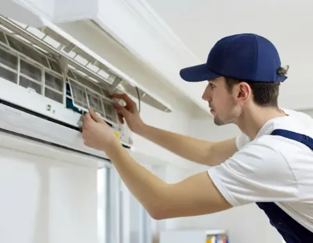 An HVAC technician works on a ductless AC unit