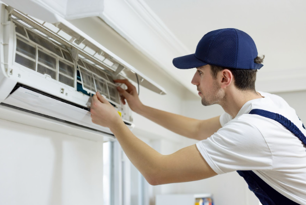 An HVAC technician works on a ductless AC unit